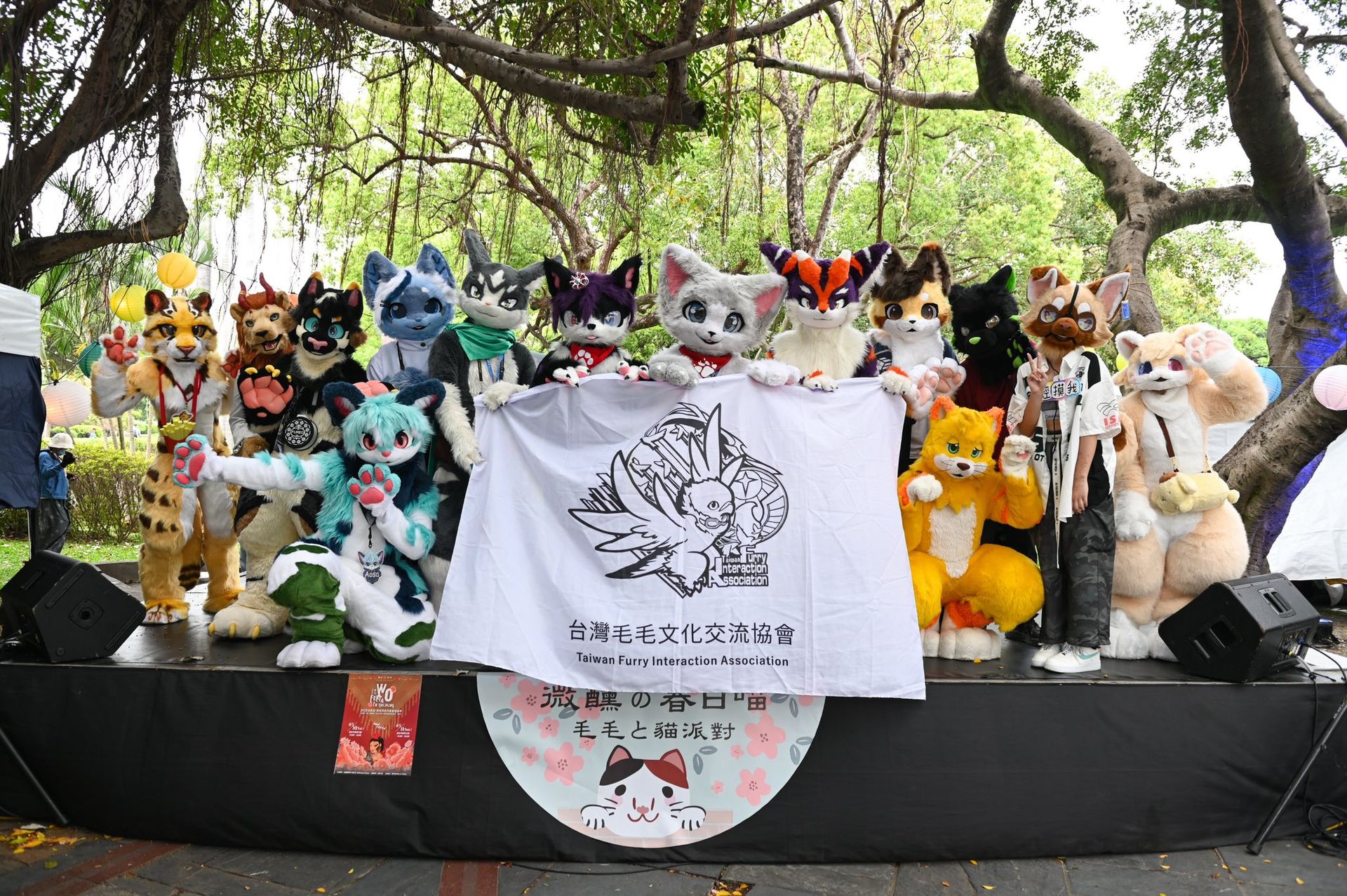 獸裝參加者列隊站在舞台上共同展示台灣毛毛文化交流協會的旗幟，慶祝《微醺の春日喵－毛毛と貓派對》活動圓滿落幕。