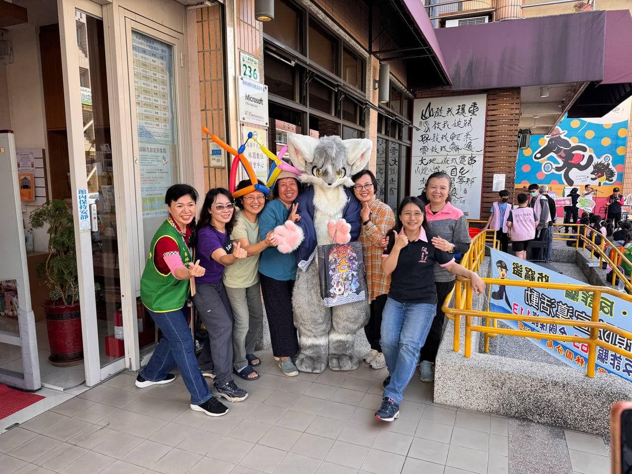 獸裝參加者與林園分館工作人員在店門口合影，其中一人頭戴造型氣球帽。