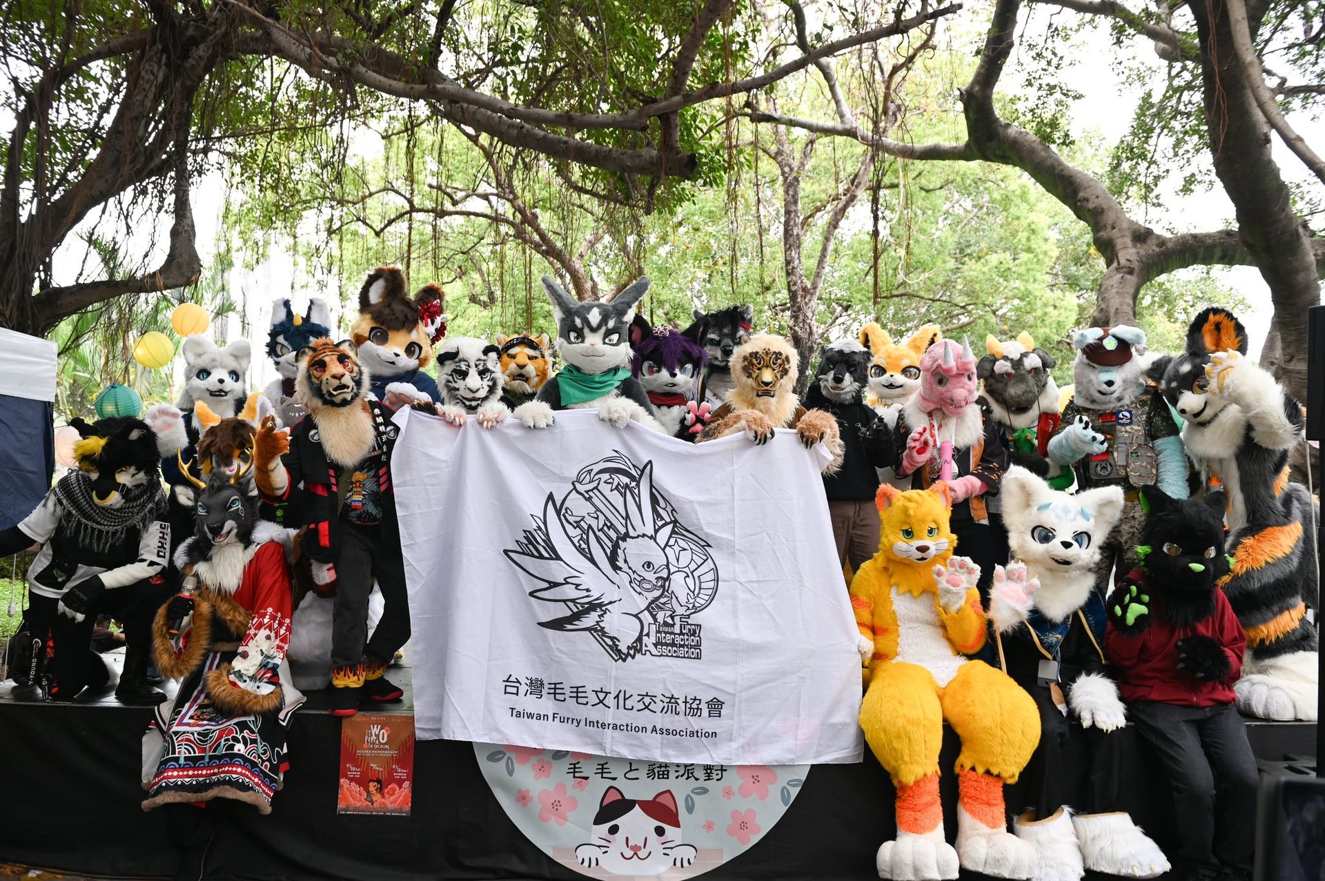 另一批獸裝參加者在同一舞台上合影，同樣舉著台灣毛毛文化交流協會旗幟，成員造型包含狼、鹿、虎、龍等各式角色。