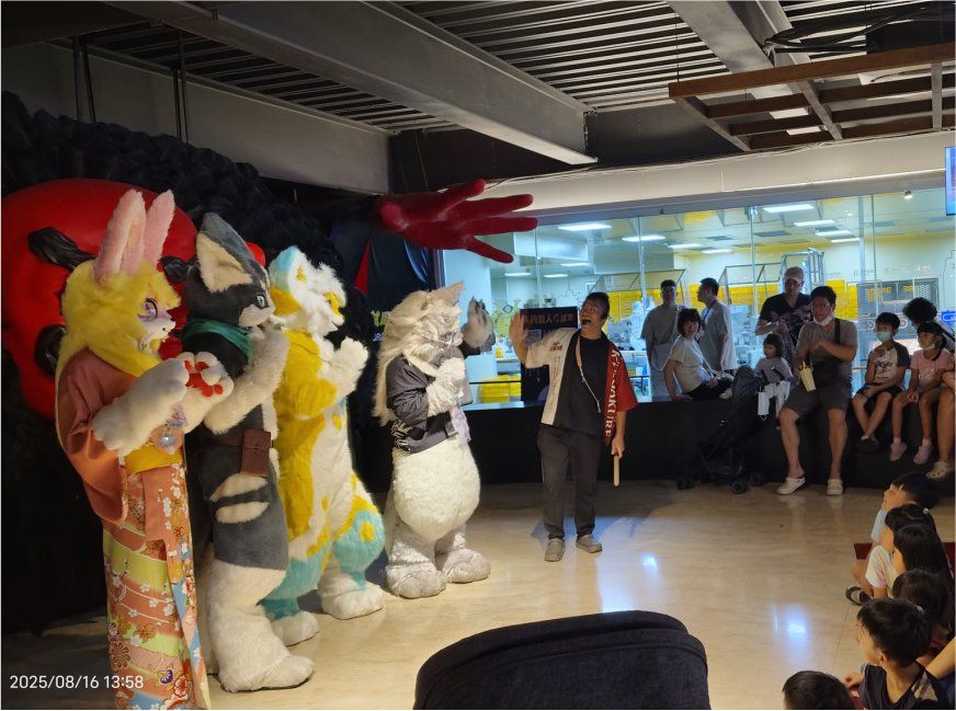多隻獸裝角色與主持人在商場內對現場觀眾表演互動，背景立著大型紅色手掌裝飾