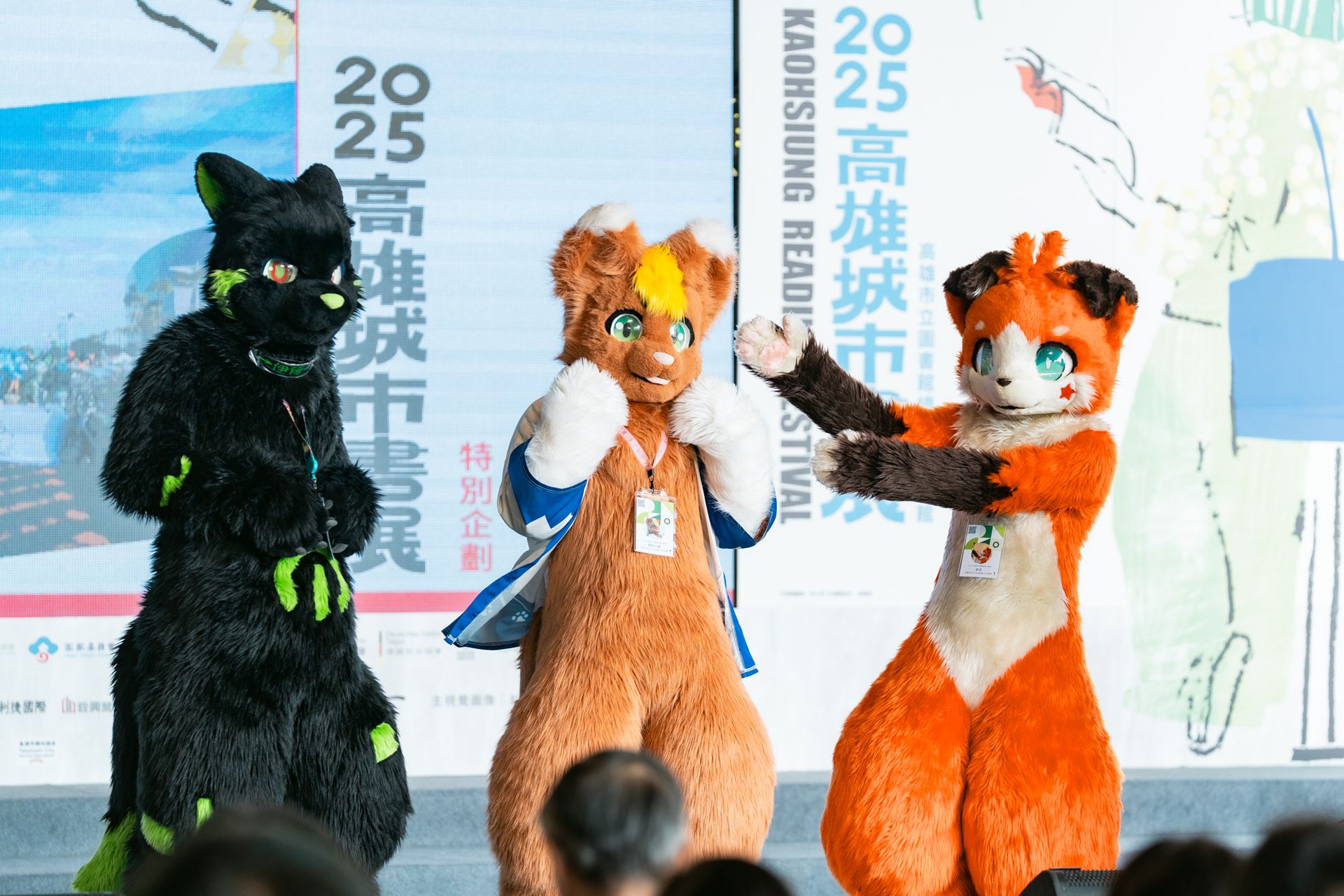 舞台上三隻獸裝角色互動表演,背景螢幕顯示「2025高雄城市書展 KAOHSIUNG READING FESTIVAL」字樣