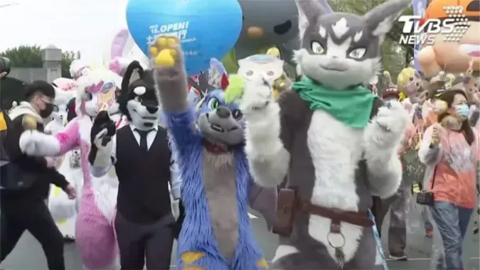A TV news screenshot with the caption "Join the joyful 2022 OPEN! Balloon Parade at Kaohsiung Dream Mall," showing fursuiters waving to the crowd behind barriers.