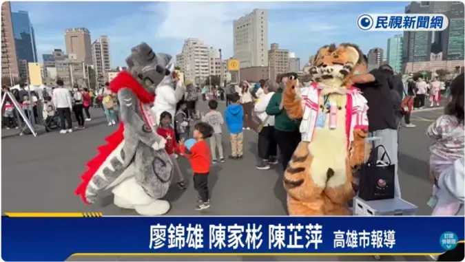 An FTV News still of a gray dragon-style and an orange tiger fursuiter interacting with children at the event.